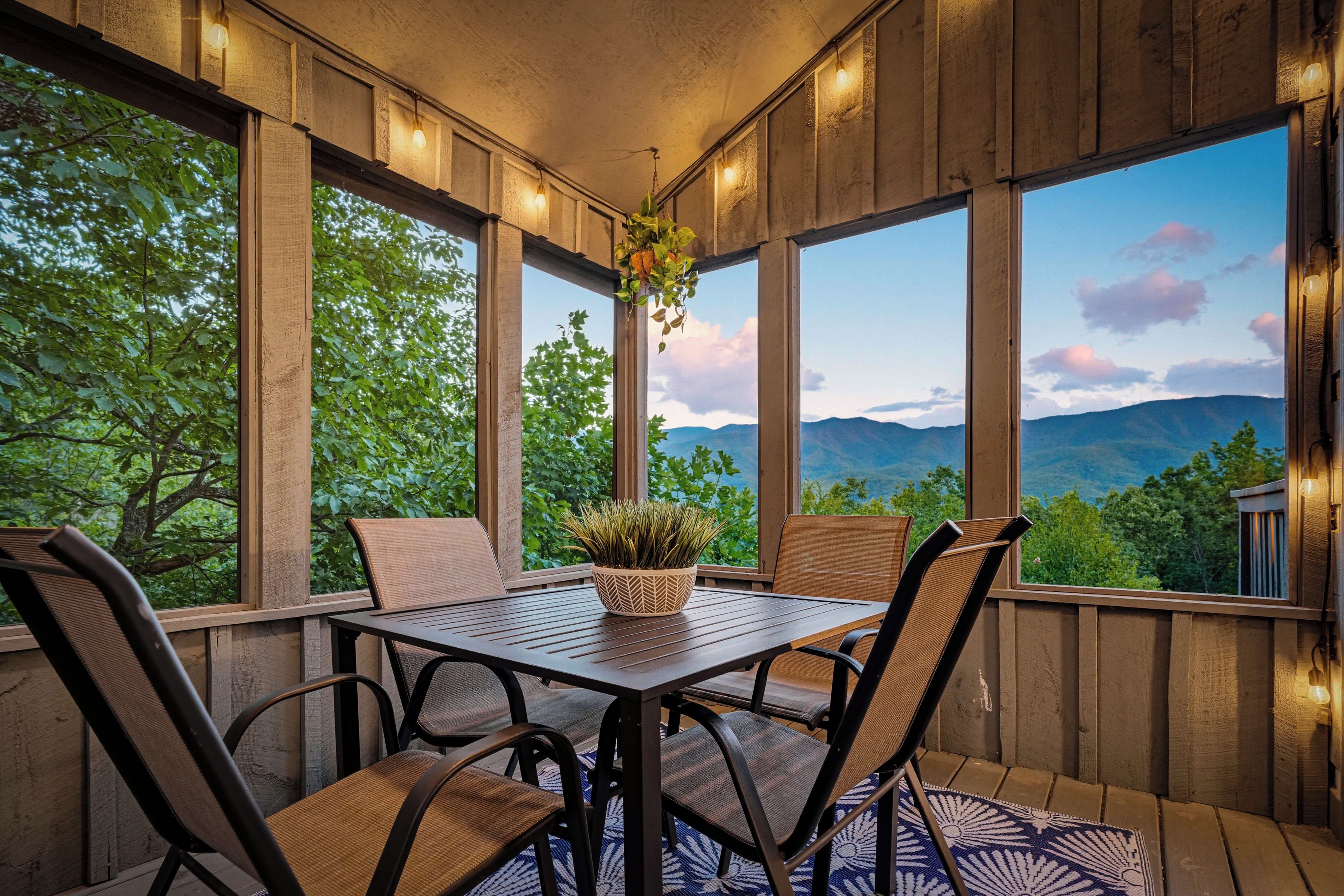 A wooden deck with a table and chairs, overlooking a mountainous landscape.