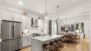 A modern kitchen with stainless steel appliances, a large island with bar stools, and pendant lighting. - Next to Dragonfly Pool with Designer Interiors, LSV (golf cart), Bikes, and More (Santa Rosa Beach)