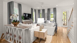 A modern living room with a white sofa, a TV, and a wooden coffee table. - Next to Dragonfly Pool with Designer Interiors, LSV (golf cart), Bikes, and More (Santa Rosa Beach)