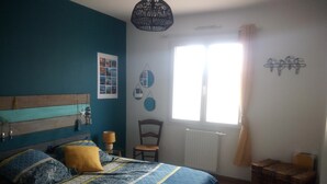 A bedroom with a bed, a chair, a window, and a radiator. - Beautiful volumes for this pretty house 50 m from the sea. (La Guérinière)