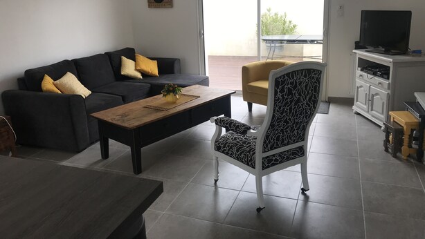 A modern living room with a sofa, coffee table, armchair, and a TV on a cabinet. - Beautiful volumes for this pretty house 50 m from the sea. (La Guérinière)