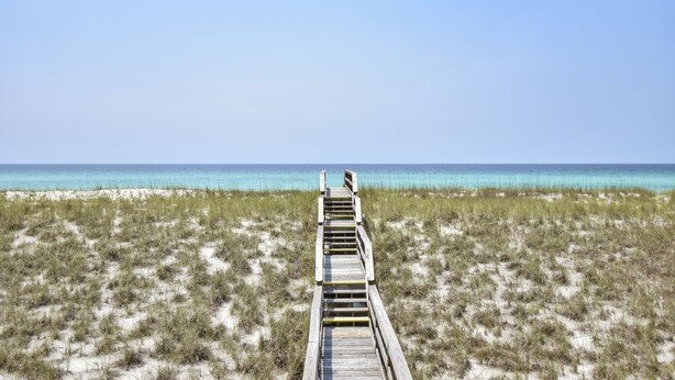 Ein hölzerner Steg führt zum Strand.