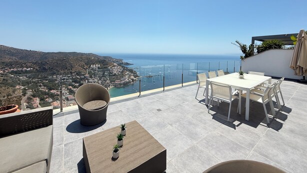 A terrace with a table and chairs, a cushioned chair, and a small table with potted plants. - Agi Canyelles Mar Casa 1 Casa for rent in Roses Girona. (Roses)