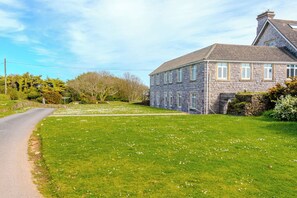 A stone house with a paved driveway and a grassy lawn. - 9 The Downs, modern apartment in stunning location in Thurlestone, South Devon (Thurlestone)