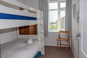 A bunk bed room with a window, a chair, and a door. - 9 The Downs, modern apartment in stunning location in Thurlestone, South Devon (Thurlestone)