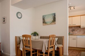 Un comedor con una mesa y sillas, un reloj en la pared y un cuadro sobre la mesa.