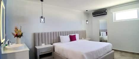 Un dormitorio moderno con una cama grande, mesitas de noche, un espejo y un equipo de aire acondicionado instalado en la pared.