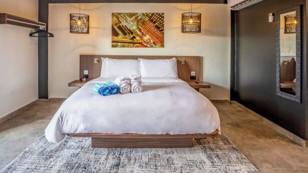 Una habitación de hotel moderna con una cama grande, un cuadro en la pared y un equipo de aire acondicionado.