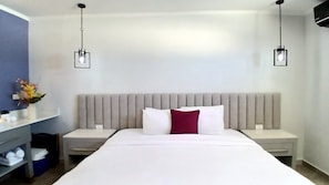 A hotel room with a large bed, two bedside tables, a nightstand, a wall-mounted shelf with a vase, and two hanging pendant lights. - Bushiri's Long Life Building-Studio-Sleeps 2 #10 (Oranjestad-West)