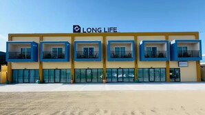 A building with a 'LONG LIFE' sign, multiple balconies, and a clear sky.