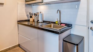 Una cocina moderna con gabinetes blancos, un lavamanos de acero inoxidable y un microondas.