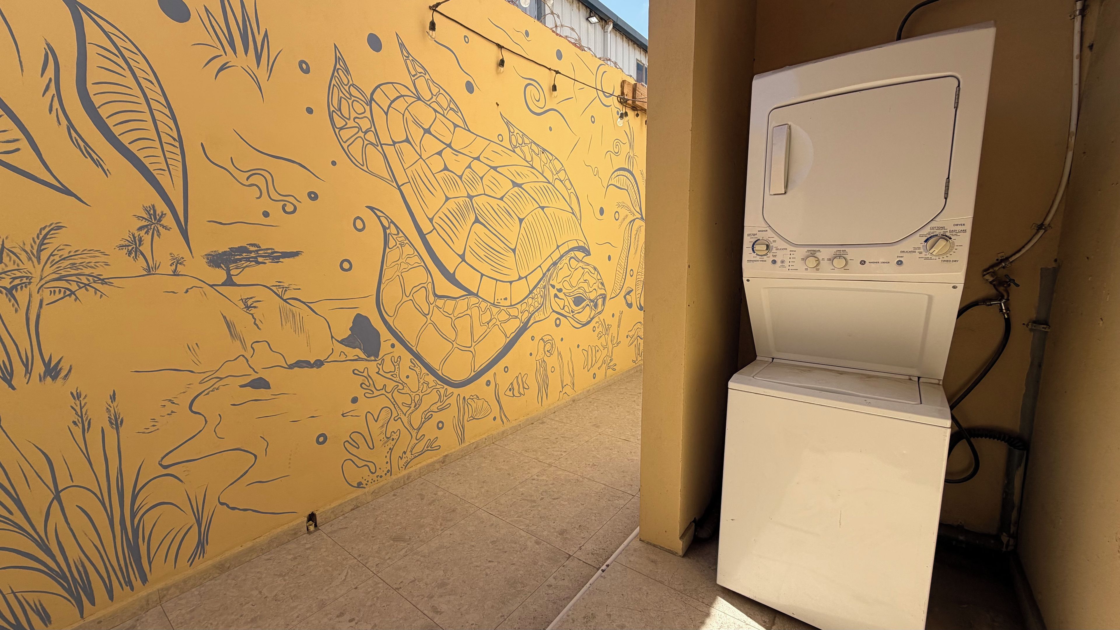 Un espace buanderie équipé d’un lave-linge et orné d’une fresque murale.