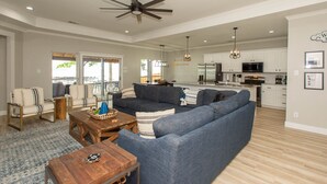 A spacious living room with a blue sofa, wooden coffee table, and a view to the outdoor patio. - 2 Free Kayaks! Gorgeous Home with Great Lakefront Outdoor Space (Mabank)
