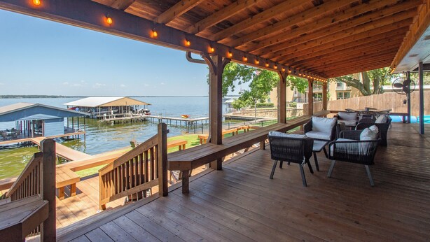A wooden deck with outdoor seating and a view of a marina. - 2 Free Kayaks! Gorgeous Home with Great Lakefront Outdoor Space (Mabank)