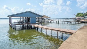 A dock extending into calm water with a covered seating area and a small building. - 2 Free Kayaks! Gorgeous Home with Great Lakefront Outdoor Space (Mabank)