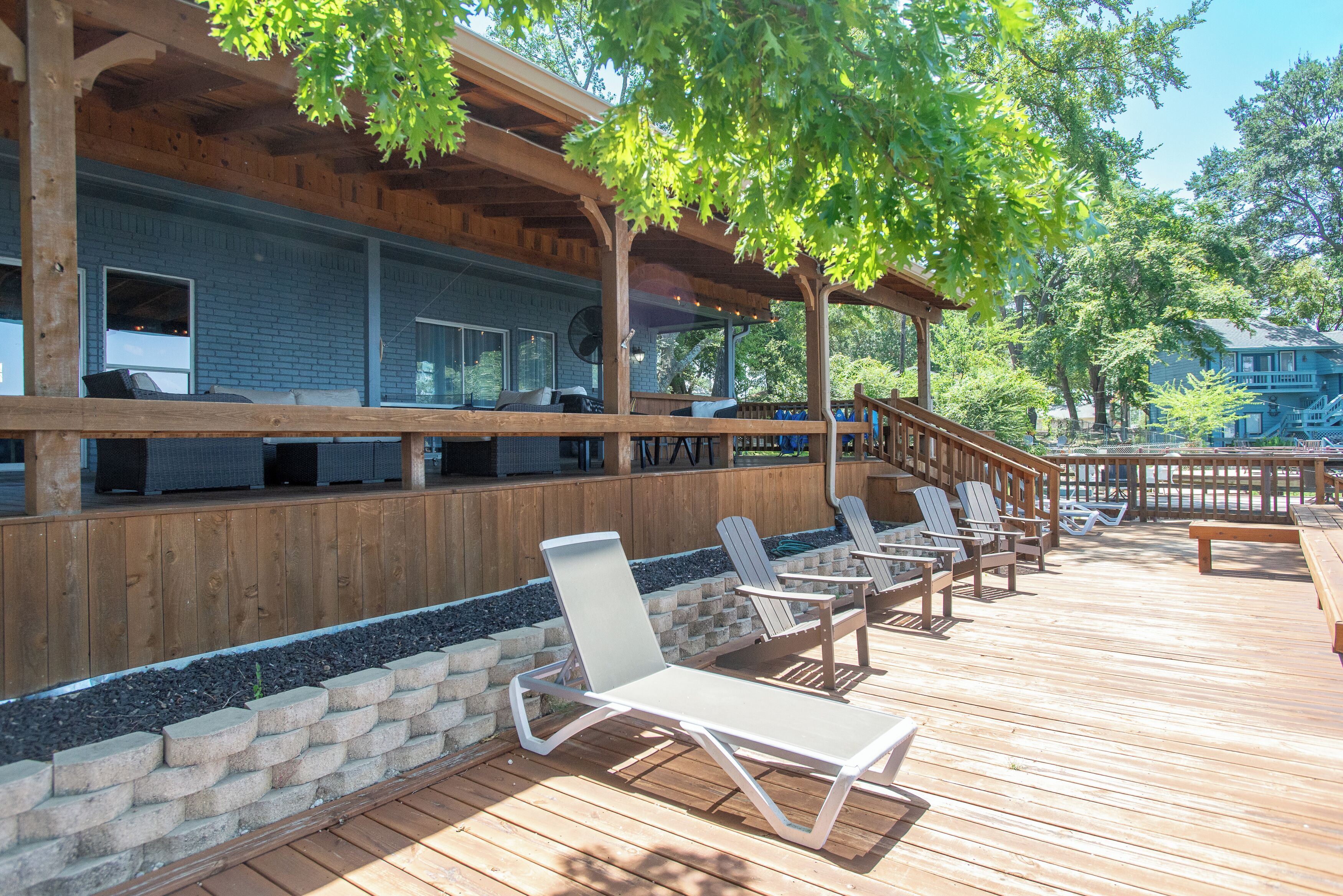 A wooden deck with lounge chairs and a covered bar area.