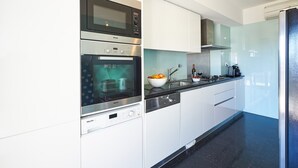 A modern kitchen with stainless steel appliances, a glass backsplash, and a black countertop. - La Scala Sea Views - by Portugal Portfolio (Cascais)