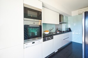 Een moderne keuken met roestvrijstalen apparatuur, een glazen spatwand en een zwart aanrecht.