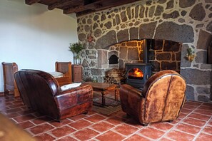 A cozy room with a stone fireplace, leather armchairs, and a wooden table.
