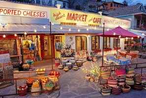 Un marché et un café avec des places assises à l’extérieur, proposant divers produits alimentaires, et une enseigne indiquant qu’il sert des repas pour le petit-déjeuner, le déjeuner et le dîner.