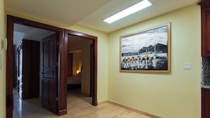 A hallway with wooden flooring, a door leading to another room, and a framed black and white painting on the wall. - 7th Floor Ocean View. Sleeps 8. 3 Beds 3 Bath (Jacó)