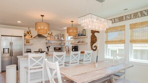 Een moderne keuken met witte kasten, een houten eettafel en hanglampen.