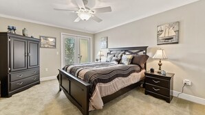 A bedroom with a bed, a nightstand, a dresser, a ceiling fan, and a window. - Seaside Treasure - Beach, Pool, Casino, Family Activities, Sunsets, Relax. (Biloxi)