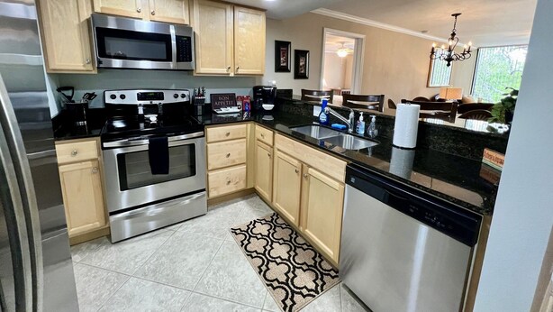 A modern kitchen with stainless steel appliances, wooden cabinets, and a black countertop. - Seaside Treasure - Beach, Pool, Casino, Family Activities, Sunsets, Relax. (Biloxi)