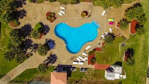 An aerial view of a property with a large swimming pool, surrounded by landscaped areas and a few buildings. - Seaside Treasure - Beach, Pool, Casino, Family Activities, Sunsets, Relax. (Biloxi)