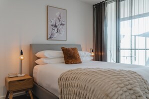 Relax in comfort with a large bed, multiple pillows, and a cozy throw blanket.