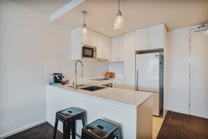 Kitchen features a central island with sink and oven, stainless steel refrigerator, and microwave.