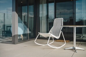 Relax in a serene outdoor space with a woven chair and simple table, surrounded by natural beauty.