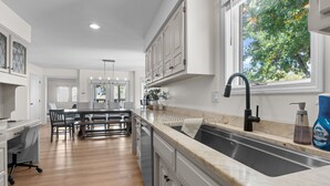 A modern kitchen with a central island, a large window, and a sink. - Spacious KC Home - Pickleball, Mini Golf, Gym, Luxurious Bathrooms, Swim Spa (Bonner Springs)