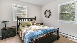 A bedroom with a bed, nightstand, lamp, and a wall mirror. - 3 BR Family Friendly Rambler (Hope Mills)