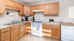 A kitchen with wooden cabinets, a stainless steel sink, a white stove, and a dishwasher. - 3 BR Family Friendly Rambler (Hope Mills)