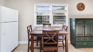 A dining area with a wooden table and chairs, a white refrigerator, and a green cabinet. - 3 BR Family Friendly Rambler (Hope Mills)