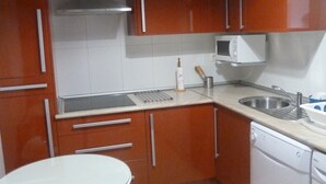 A compact kitchen with wooden cabinets, a microwave, a sink, and a dishwasher. - VoT Rupurupay B (Aldeadávila de la Ribera)