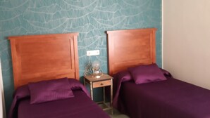 A room with two beds, each with a wooden headboard and purple bedding. There is a small bedside table with a lamp between the beds. - VoT Rupurupay B (Aldeadávila de la Ribera)