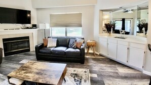 Een moderne woonkamer met een zwarte leren bank, een salontafel en een open haard.