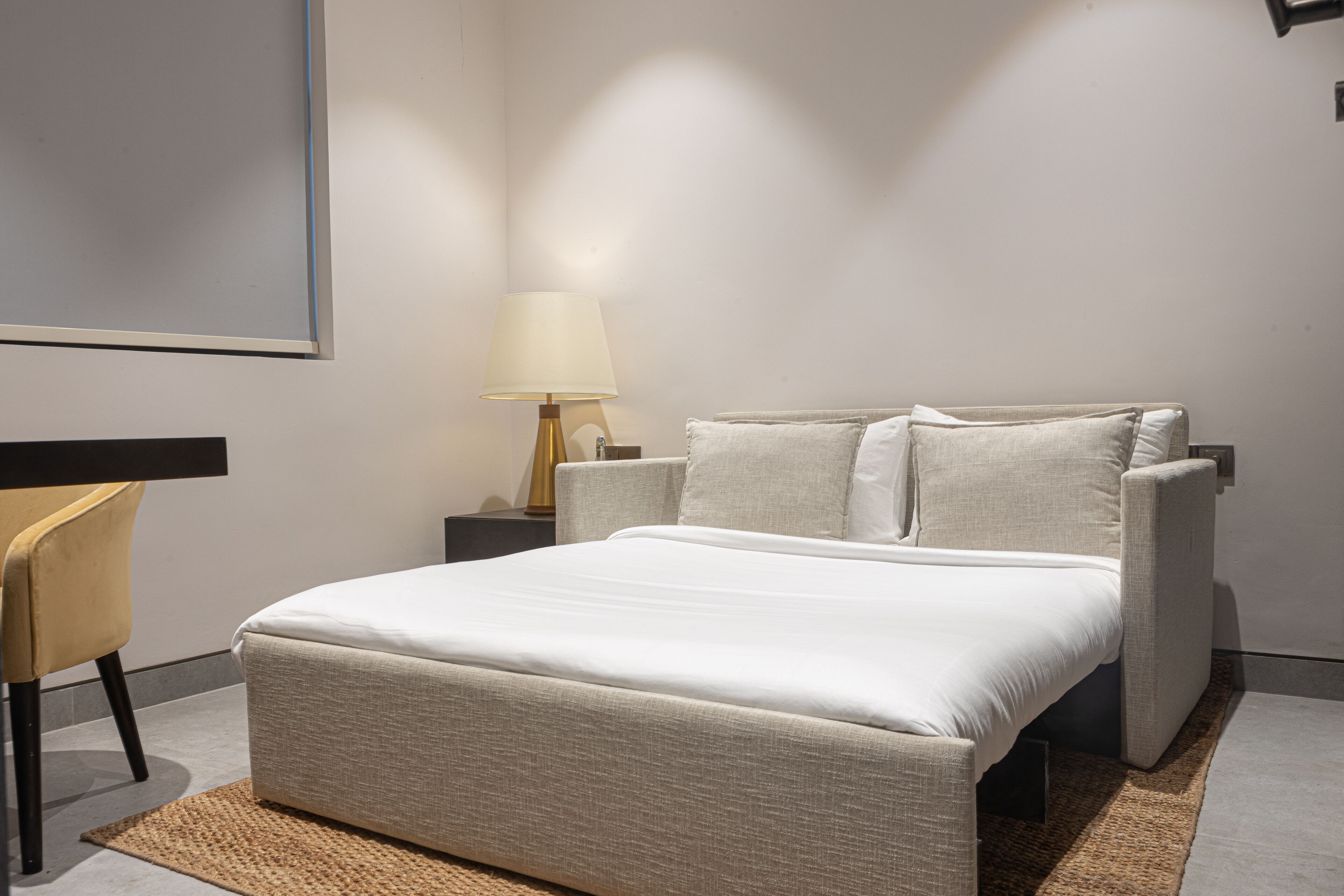 Et moderne soveværelse med en seng, sengeborde, en lampe og en stol.