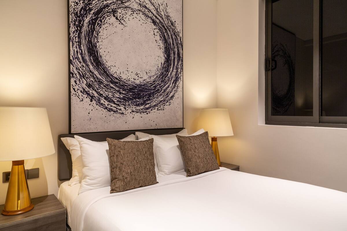 Una habitación de hotel con una cama grande, dos lámparas de noche y una obra de arte en la pared.