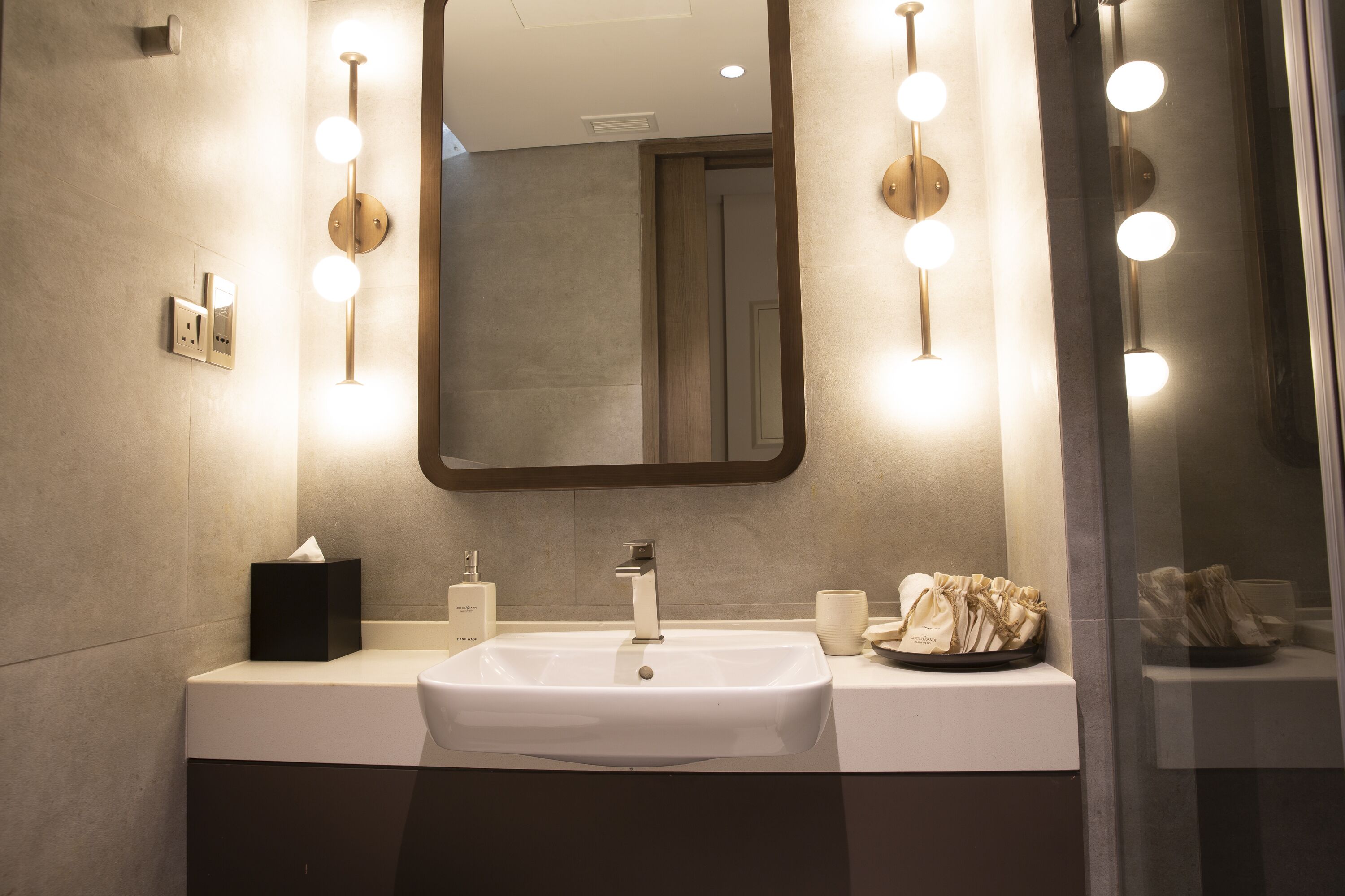 A modern bathroom with a white sink, a large mirror, and wall-mounted lights.