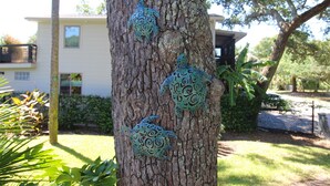 Un arbre orné de trois décorations métalliques en forme de tortue.