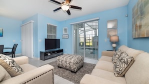 A living room with a TV, sofa, and a ceiling fan. - Family-Friendly 4BR Home w/ Pool, Resort Perks, & Disney Nearby (Kissimmee)