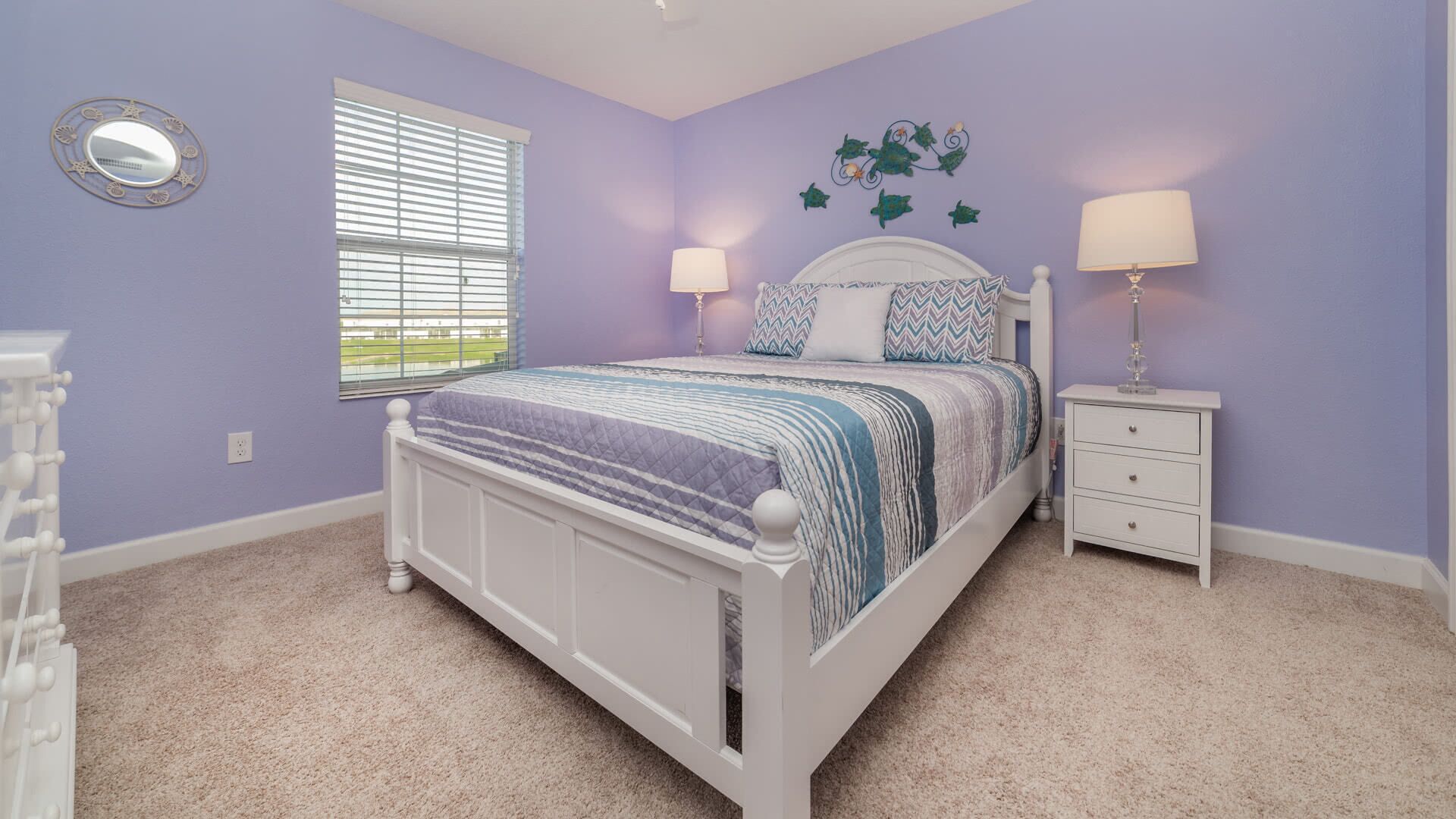 A bedroom with a bed, nightstands, a dresser, a window with blinds, and a wall decoration.