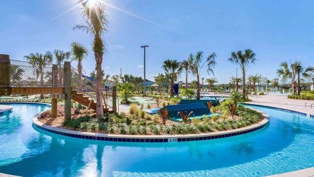 A swimming pool with a surrounding deck, palm trees, and a clear blue sky. - Family-Friendly 4BR Home w/ Pool, Resort Perks, & Disney Nearby (Kissimmee)