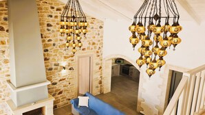 A stone-walled interior with a blue sofa, a fireplace, and hanging lamps. - Villa Lisaya, a haven of peace with sea view and swimming pool, in a Natura 2000 area! (PALELONI)