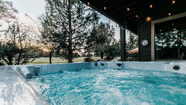 A hot tub with a view of trees and a building in the background. - Golf-Front Luxury | 3 King Suites | Private Hot Tub | Eagle Crest Resort (Redmond)
