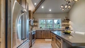 A modern kitchen with stainless steel appliances, wooden cabinets, and a large island. - Golf-Front Luxury | 3 King Suites | Private Hot Tub | Eagle Crest Resort (Redmond)