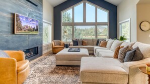 A spacious living room with a large window, a fireplace, and a comfortable seating area. - Golf-Front Luxury | 3 King Suites | Private Hot Tub | Eagle Crest Resort (Redmond)